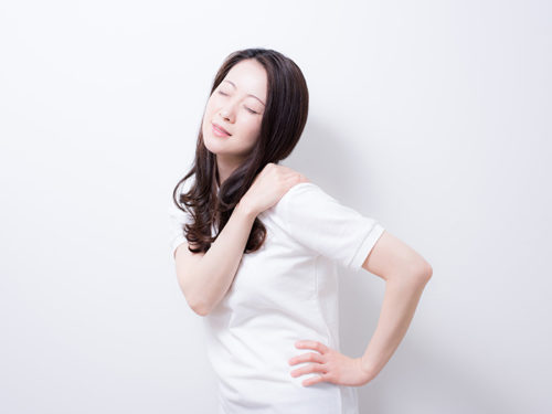 腰に手を当て肩を触る女性